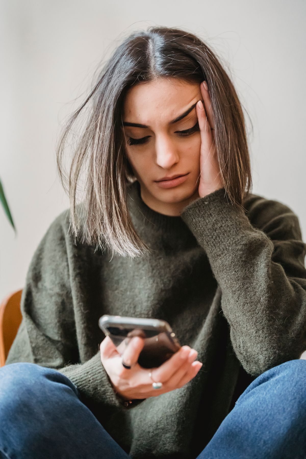Orolig ung kvinna som tittar på sin mobiltelefon